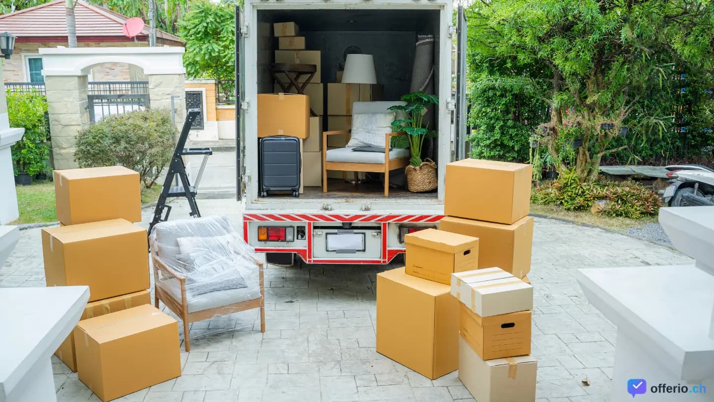 Umzugsmitarbeiter tragen Möbel und Kartons aus einem Transporter
